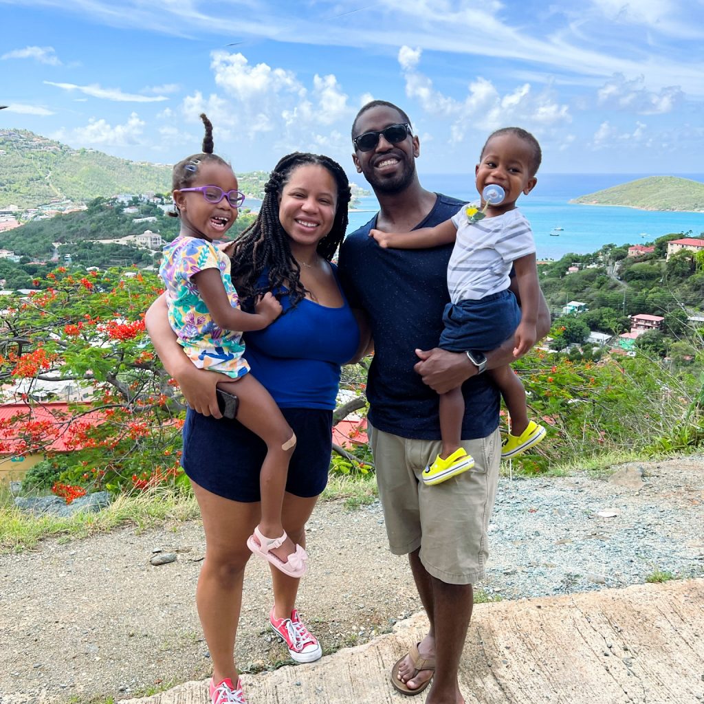 Mom and dad holding two children with mountains and the ocean in the background
