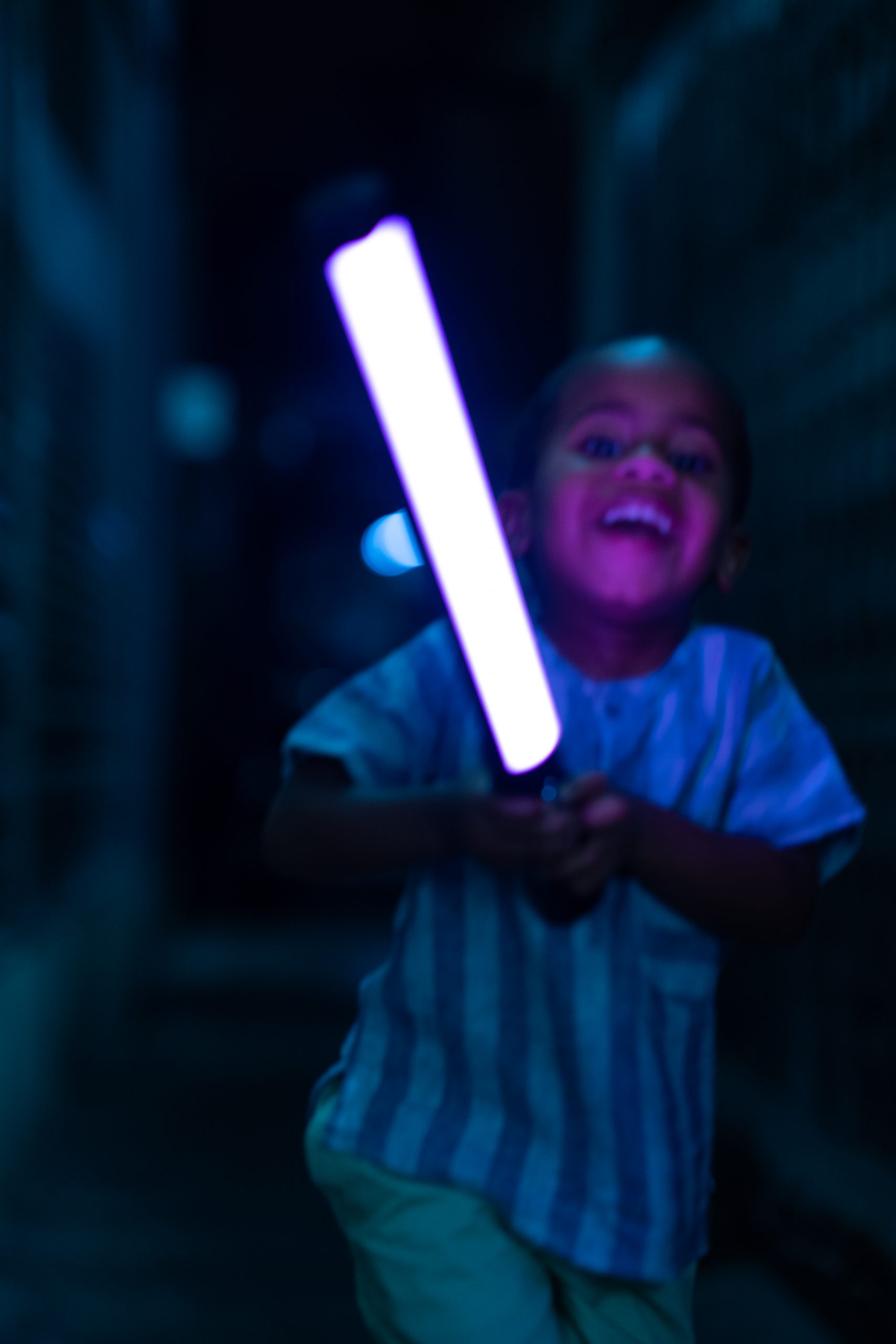 Son holding a light stick, illuminated with a black light effect